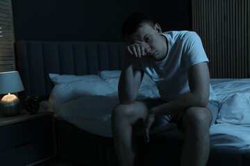 Frustrated man suffering from insomnia on bed indoors, space for text