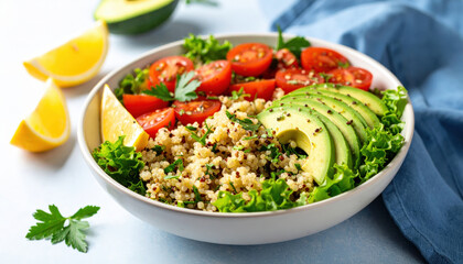 Fresh quinoa salad bowl with sliced avocado, cherry tomato, lemon wedge, and green lettuce, offering healthy and vibrant meal