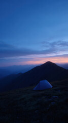 Obraz premium Tent under blue twilight sky with mountain ridge in background