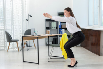 Beautiful woman doing exercise near desk in office