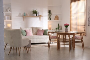 Stylish dining table with chairs and comfortable sofa in room. Interior design