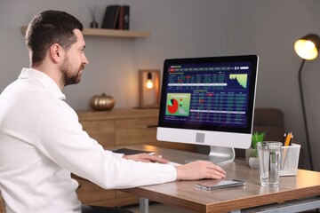 Stock exchange. Man analysing financial market on computer at desk indoors