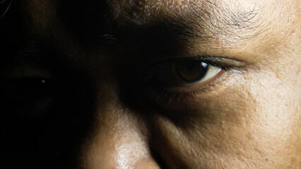 Close-up of brown eyes from Indonesian male, angled gaze with sharp focus on irises, intimate...