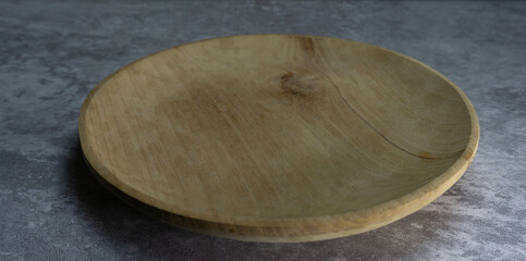 Round wooden plate on neutral gray background, rustic food styling element with organic material,...