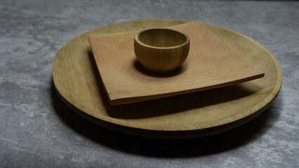 Stacked wooden plate and bowl on gray surface, natural texture and simple layout for rustic kitchen design or food styling usage in editorial visuals