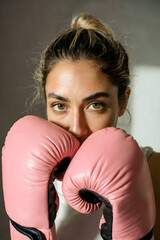 Strength and Style: Intense Portrait of a Young Woman in Pink Boxing Gloves with a Steely Gaze and Casual Power