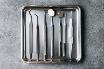 Dental tools rest on a metal tray. Concept: healthcare, dentistry. Useful for marketing, dental clinic ads, web design.