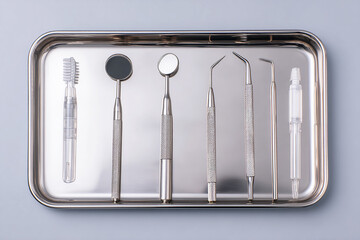Dental tools lie neatly on a metal tray. Clean, modern look for healthcare, dental hygiene, and oral health-related design or editorial content.