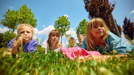 Children have fun outdoors on a sunny day, relaxing on the grass in a park, illustrating the ideas...