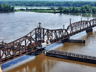 Aerial view of a Railroad locomotive pulling a freight train across the Mississippi river on the swing trestle bridge