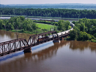 Aerial view of a Railroad locomotive pulling a freight train across the Mississippi river on a trestle bridge