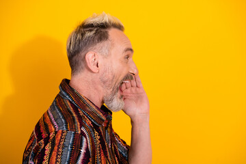Charismatic bearded gentleman in colorful shirt shouting with excitement against a vibrant yellow...