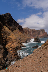Rocky cliffs and blue ocean under scattered clouds