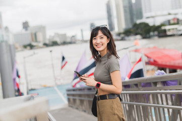 Young southeast asian woman teenager blogger using smartphone searching for travel guide. world...