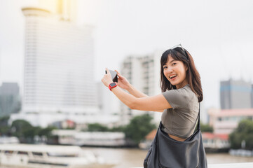 Happy solo southeast asian teenager woman blogger take photo with smartphone. World travel tourism...