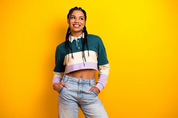 Stylish young woman with braided hair in casual attire posing confidently against a vibrant yellow...