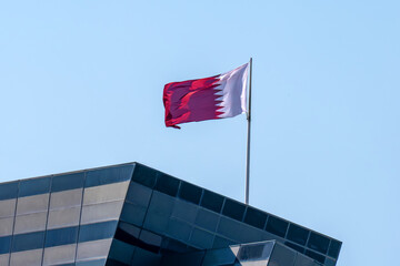 Qatar flag and blue sky, Flag of Qatar fluttering in blue sky big national symbol. Waving white and claret red Qatar flag, Independence Constitution Day. flag of Qatar on a skyscraper