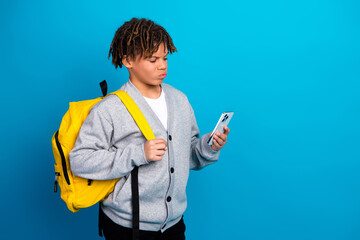 Confident schoolboy in cardigan holding phone against vibrant background, showcasing youthfulness