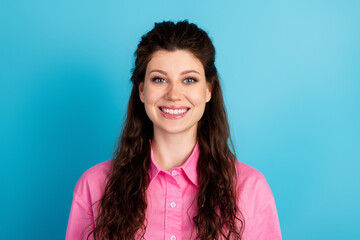 Young woman in a pink shirt smiling brightly against a vibrant blue background, showcasing modern...