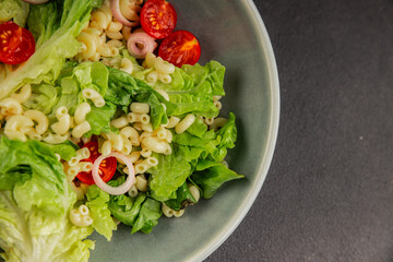 Pasta salad green leaf lettuce, tomato, pasta, onion fresh delicious gourmet food background on the table rustic food top view copy space keto and paleo diet vegan and vegetarian food