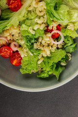 Pasta salad green leaf lettuce, tomato, pasta, onion fresh delicious gourmet food background on the table rustic food top view copy space keto and paleo diet vegan and vegetarian food