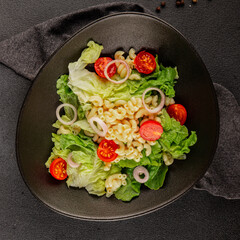 Pasta salad green leaf lettuce, tomato, pasta, onion fresh delicious gourmet food background on the table rustic food top view copy space keto and paleo diet vegan and vegetarian food