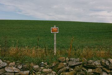 Private property sign in rural area with green field and stone wall