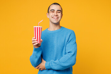 Young smiling happy middle eastern man wear blue sweatshirt casual clothes hold in hand cup of soda...