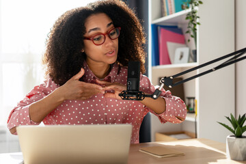 Beautiful African American woman recording podcast from her home studio