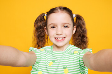 Close up little fun cute kid child girl 8-9 years old wearing green t-shirt doing selfie shot pov...