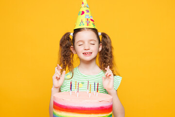 Little kid child girl 8-9 years old wear green t-shirt birthday cone hat hold cake with candles...