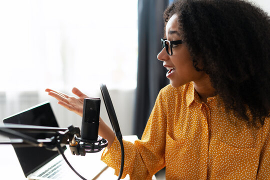 Young African American woman recording podcast with professional microphone and laptop
