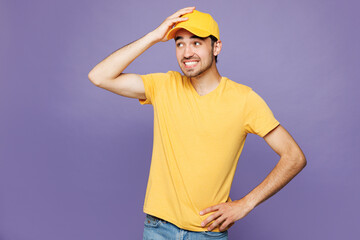 Professional confused sad delivery guy employee man wear yellow cap t-shirt uniform workwear work...