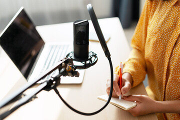 Content creator taking notes while recording a podcast using a professional microphone