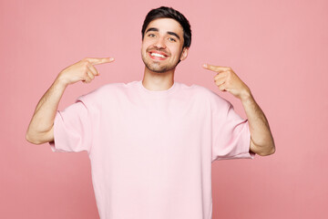 Young smiling happy cool fun Caucasian man he wear t-shirt casual clothes point index fingers on...