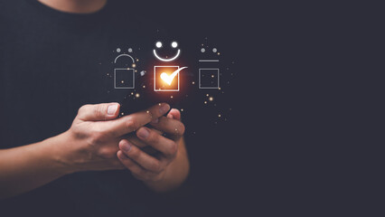 Concept of assessing customer satisfaction with service. Asian man is using a smart phone and is pressing a smiling emoticon