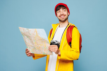 Traveler smiling happy man wear hat yellow casual clothes read paper map isolated on plain pastel blue background Tourist travel abroad in free spare time rest getaway Air flight trip journey concept