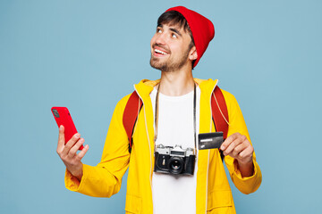 Traveler man wear yellow casual clothes hold credit card use mobile cell phone isolated on plain...