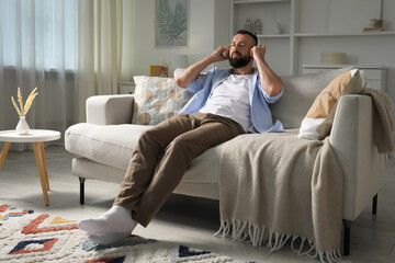 Obraz premium Harmony. Man listening to music in headphones on sofa at home