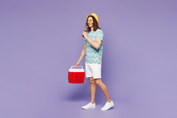 Full body young man wear blue t-shirt yellow hat sunglasses rest near hotel pool hold beach cooler...