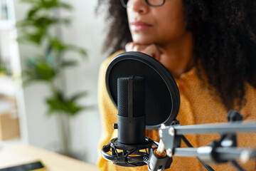 Young woman recording a podcast from home using a professional microphone