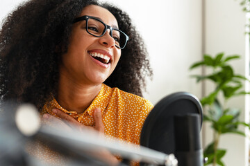 African American content creator recording podcast and laughing with microphone
