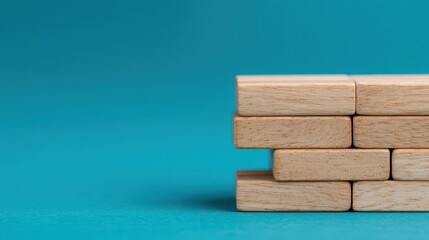 Stacked wooden blocks arranged in a neat formation on a turquoise surface with a plain background.