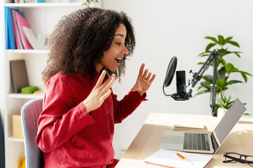 Young smiling African American woman recording podcast in her home studio