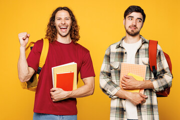 Young sad upset two friends men student they wear casual clothes backpack bag together hold books...