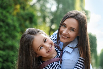 Fototapeta premium Family portrait of smiling mother and daughter in park