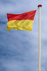 red and yellow lifeguard on duty flag on the beach in the Netherlands