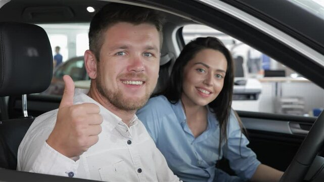 Happy couple celebrating a car purchase with a thumbs-up