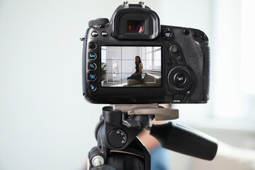 Woman on sofa in studio, focus on video camera recording her