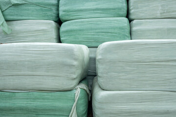 Obraz premium foil-wrapped square bales on farm in storage area
